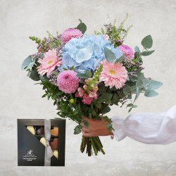 Smuk blomsterbuket med lyseblå hortensia i midten omgivet af lyserøde blomster.