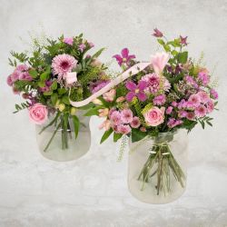 Mor og barn buketter i lyserøde og lilla nuancer med roser og krysantemum i glasvaser, bundet sammen med silkebånd.