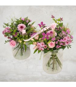 Mor og barn buketter i lyserøde og lilla nuancer med roser og krysantemum i glasvaser, bundet sammen med silkebånd.